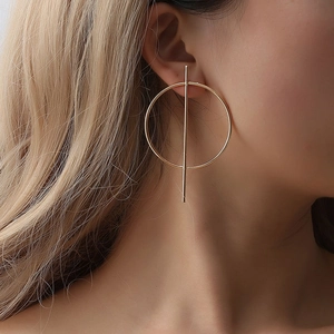 Detail of geometric gold drop earring with large hoop and vertical bar on model