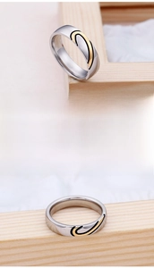 Macro detail of polished stainless steel couple ring with gold and black wave design