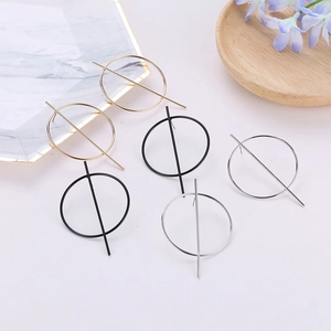 Detail view of oval resin earrings in gold, black, and silver on an aesthetic marble tray