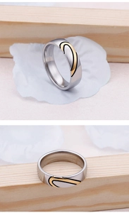 Close-up of two-tone silver and gold heart pattern couple rings on wooden background
