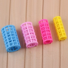 Detailed view of colorful hair roller set in blue, pink, and yellow on wood surface