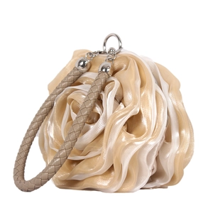 Detailed close-up of champagne silk rose petals and woven handle on the evening handbag