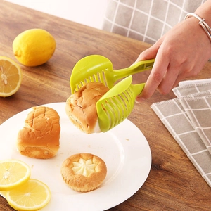 Green handheld tomato and lemon slicer guide for safe fruit and vegetable cutting