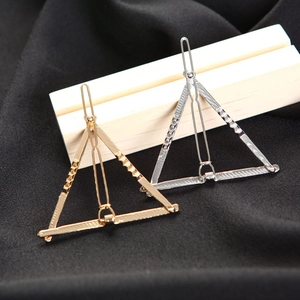 Minimalist geometric triangle hair clips in gold and silver finish on textured wood
