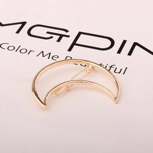 Macro view of a gold-tone crescent moon hair clip with a classic metal spring fastener