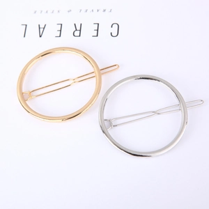 Minimalist gold and silver geometric circular hair clips on a stylish magazine