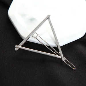 Macro shot of minimalist silver metal triangle hair clip on white ceramic plate