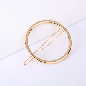 Detailed view of a minimalist round gold metal hair clip with a polished finish