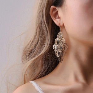 Elegant gold multi-layered hollow leaf drop earrings worn by a female model