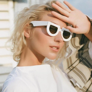 Close-up of white geometric sunglasses worn by a model in bright outdoor natural light