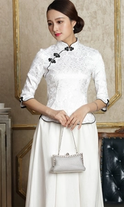 Silberne Abendtasche mit Perlen, getragen von einem Model in eleganter weißer Qipao