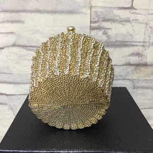 Macro detail of golden circular evening clutch featuring sparkling rhinestone texture