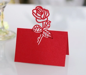 Macro shot of laser-cut rose design and pearlescent paper texture on red wedding place card