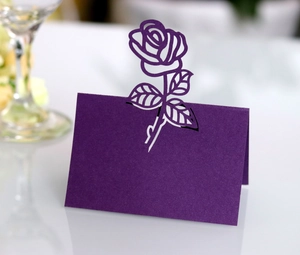 Detail of laser-cut rose hollow design on purple wedding place cards with paper texture