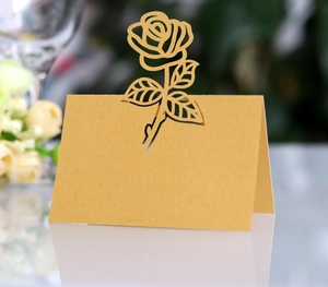 Macro shot of gold laser-cut rose wedding place cards with elegant hollow floral patterns
