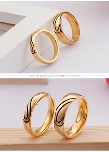 Detailed view of polished gold stainless steel couple rings with black enamel swirls