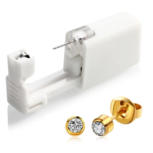 Close-up of a disposable ear piercing tool with golden cubic zirconia stud earrings