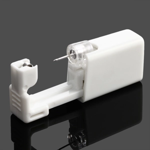Detail of disposable white ear piercing tool with stainless steel needle on black background