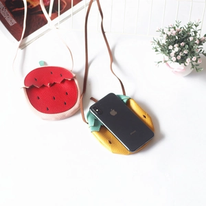 Close-up of strawberry and pineapple kids crossbody bags in litchi textured leather