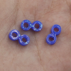 Macro detail of three blue synthetic opal infinite beads on palm for size scale