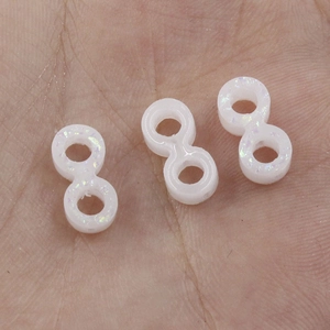 Macro shot of three small white synthetic opal infinite beads on a palm for DIY jewelry