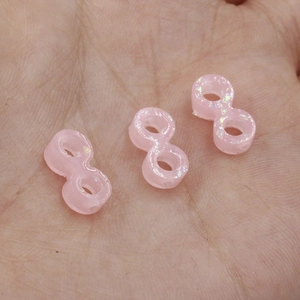 Macro shot of three pink pearlescent infinity opal beads on hand showing small details