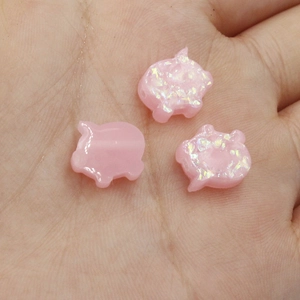 Macro shot of three pink pig opal beads held in hand showing unique shimmer and tiny DIY holes
