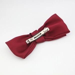 Detail of red oversized satin bow hair clip with silver metal spring fastener and handmade label