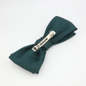 Detail of forest green satin double bow headband with a silver metal spring hair clip