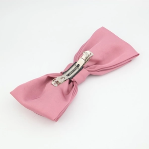 Detailed macro view of pink satin bow hair clip with handmade label and metal spring clip