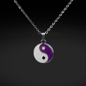 Macro detail of stainless steel Tai Chi Yin Yang pendant with purple and white enamel