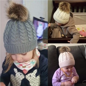 Detailed cable knit texture and faux fur pom-pom on baby winter hats in grey white and pink