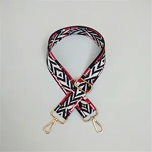 Close-up of ethnic geometric woven bag strap with golden metal hooks and adjustable buckle