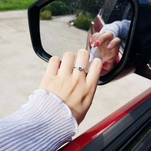 Silver star ring with blue and clear gems worn on hand near car mirror reflection