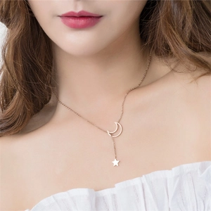 Rose gold moon and star pendant necklace worn by a model in a close-up lifestyle shot