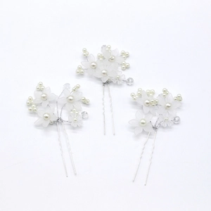 Detail of three U-shaped hair pins with white frosted flowers and pearl beads on silver metal