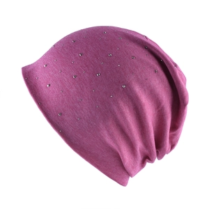 Detailed close-up of rose red knitted beanie with silver metal stud embellishments