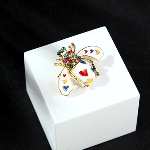 Detailed macro shot of a gold bee brooch with white enamel wings and colorful rhinestones