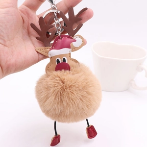 Close-up of a Christmas reindeer plush pompom keychain with a red hat and silver ring