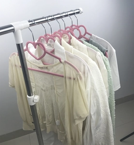 Pink heart-shaped plastic clothes hangers with metal hooks hanging on a metal garment rack