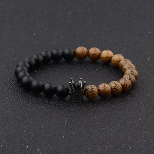 Detail of beaded bracelet with black matte beads, wood grain beads and metal crown charm