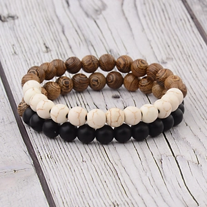 Detail view of handmade wood and marble bead bracelets on a vintage grey background