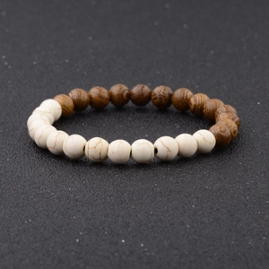 Macro detail of natural wood grain and white turquoise beads on a minimalist bracelet