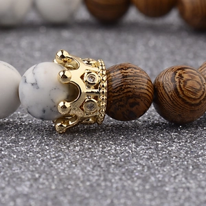 Macro detail of wooden and marble beads featuring a gold crown charm with crystals