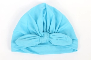 Detail of baby turban hat in light blue with a decorative front knot on white background