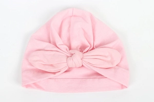 Detail of baby turban hat in soft light pink fabric with a large knot bow decoration