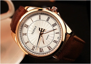 Close-up of beige watch dial with Roman numerals and golden case on brown leather strap