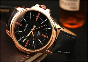 Detail view of a luxury men's quartz watch with rose gold case and black leather strap