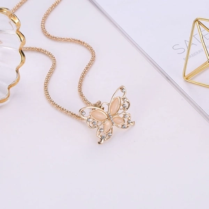 Collar de mariposa calado dorado con piedras de ópalo y pedrería blanca en fondo blanco