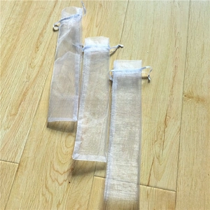 Three sizes of white organza drawstring bags for jewelry packaging on a wood surface